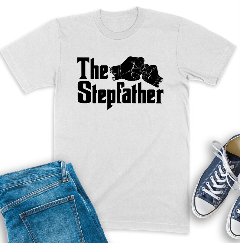 K&ouml;nnte beinhalten: Wei&szlig;es T-Shirt mit schwarzem Text "The Stepdad" und zwei sich sto&szlig;enden F&auml;usten.