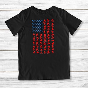 May include: Black t-shirt with a red, white, and blue American flag design. The flag is made up of silhouettes of people in various wrestling poses.