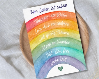 May include: A rectangular card featuring a watercolor rainbow with the German text Das Leben ist schön, Tanz aus der Reihe, Lass dich verzaubern, Hab große Träume, Glaub an Wunder, Fühl dich frei, Lache laut and a small green heart icon.