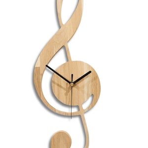 May include: A wooden wall clock shaped like a treble clef with black hands and a gold centre. The clock face is in the centre of the treble clef.