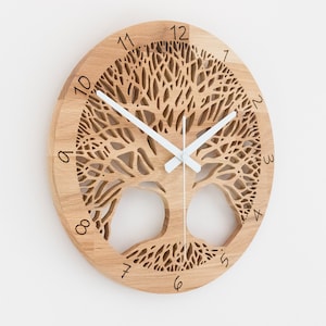 Pode incluir: Um relógio de parede redondo de madeira com um design de árvore da vida. O mostrador do relógio apresenta um motivo de árvore cortado a laser, com ponteiros brancos indicando as horas. O relógio tem aproximadamente 30 cm de diâmetro.