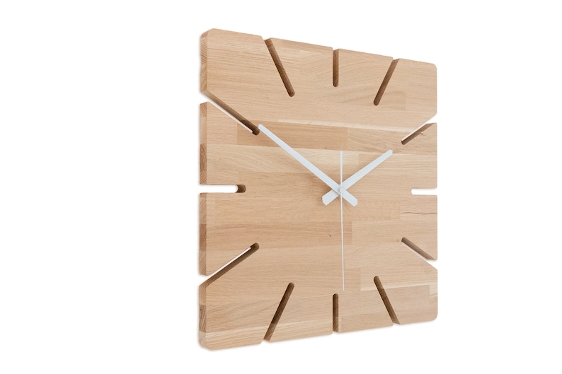 Pu&ograve; includere: Un orologio da parete quadrato in legno con lancette bianche e un design unico con tagli attorno ai bordi.