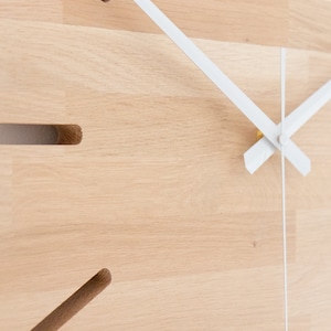 Pu&ograve; includere: Un orologio in legno con lancette bianche e un centro dorato. Il quadrante dell'orologio &egrave; in legno naturale di colore marrone chiaro.