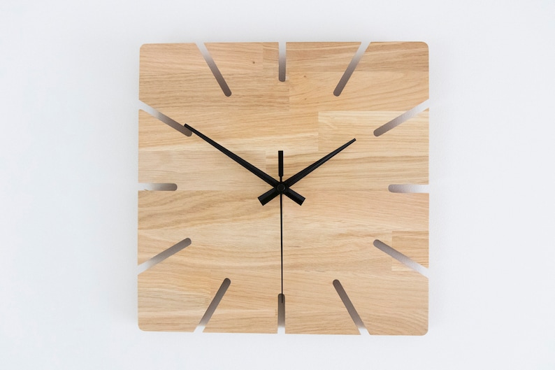 Pu&ograve; includere: Un orologio da parete quadrato in legno con lancette nere e un design unico con sezioni tagliate intorno al quadrante.