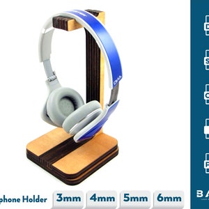 May include: A wooden headphone stand with a blue and white headphone resting on it. The stand is made of layered wood and has a square base. The text "Headphone Holder" is visible at the bottom of the image, along with the text "3mm", "4mm", "5mm", and "6mm".