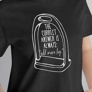 May include: A dark heather grey t-shirt with a white graphic of a stirrup and the text "The correct answer is always: 'add more leg.'"