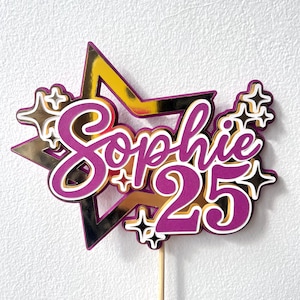 Puede incluir: Un adorno para tarta con un fondo de estrella dorada y letras moradas que dicen Sophie 25. El diseño incluye detalles en forma de estrella en blanco y negro y está sujeto a un fino palito de madera para colocarlo en la tarta.