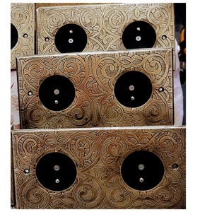 Könnte beinhalten: Nahaufnahme mehrerer verzierter, messingfarbener Steckdosenabdeckungen. Jede Abdeckung hat eine quadratische Form mit einer zentralen schwarzen kreisförmigen Steckdose und dekorativen Wirbelmustern. Die Abdeckungen sind wahrscheinlich für die Heimdekoration.