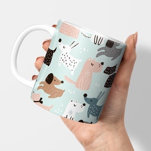 Könnte beinhalten: Weiße Keramiktasse mit hellblauem Hintergrund und einem sich wiederholenden Muster aus bunten Cartoon-Hunden.