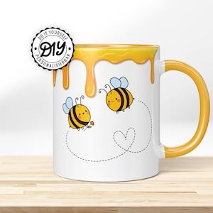 Könnte beinhalten: Weiße Keramiktasse mit gelbem Rand und Henkel. Die Tasse ist mit einem tropfenden Honigdesign und zwei Cartoon-Bienen verziert. Eine Biene hält eine Blume. Der Text "Do It Yourself DIY Personalisierbar" befindet sich auf einem schwarzen und weißen Kreisaufkleber.