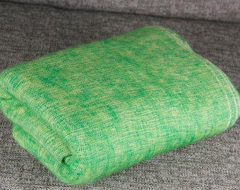 Pode incluir: Um tecido verde dobrado com um padrão verde claro e branco. O tecido é macio e tem uma superfície ligeiramente texturizada.