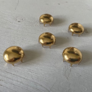 Könnte beinhalten: Fünf goldfarbene Möbelfüße aus Metall mit abgerundeter Oberseite und fünf Zacken an der Unterseite.