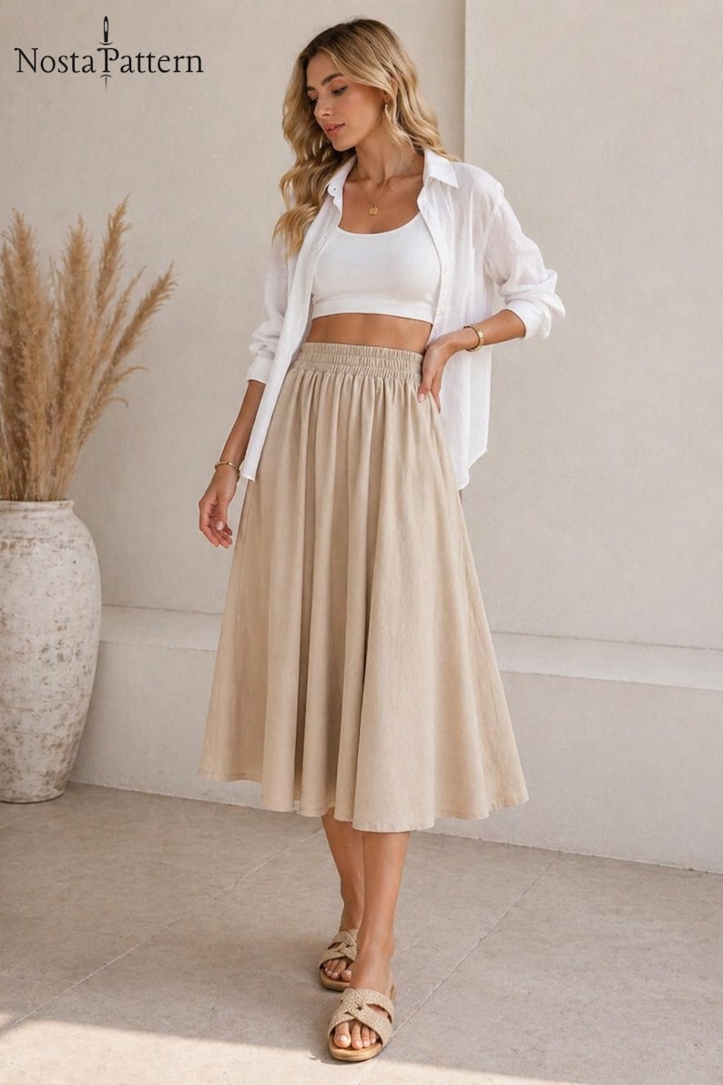 May include: A beige midi skirt with an elastic waistband is paired with a white crop top and a white button-down shirt. The outfit is completed with woven sandals. The image includes the text "Nosta Pattern" in the upper left corner.
