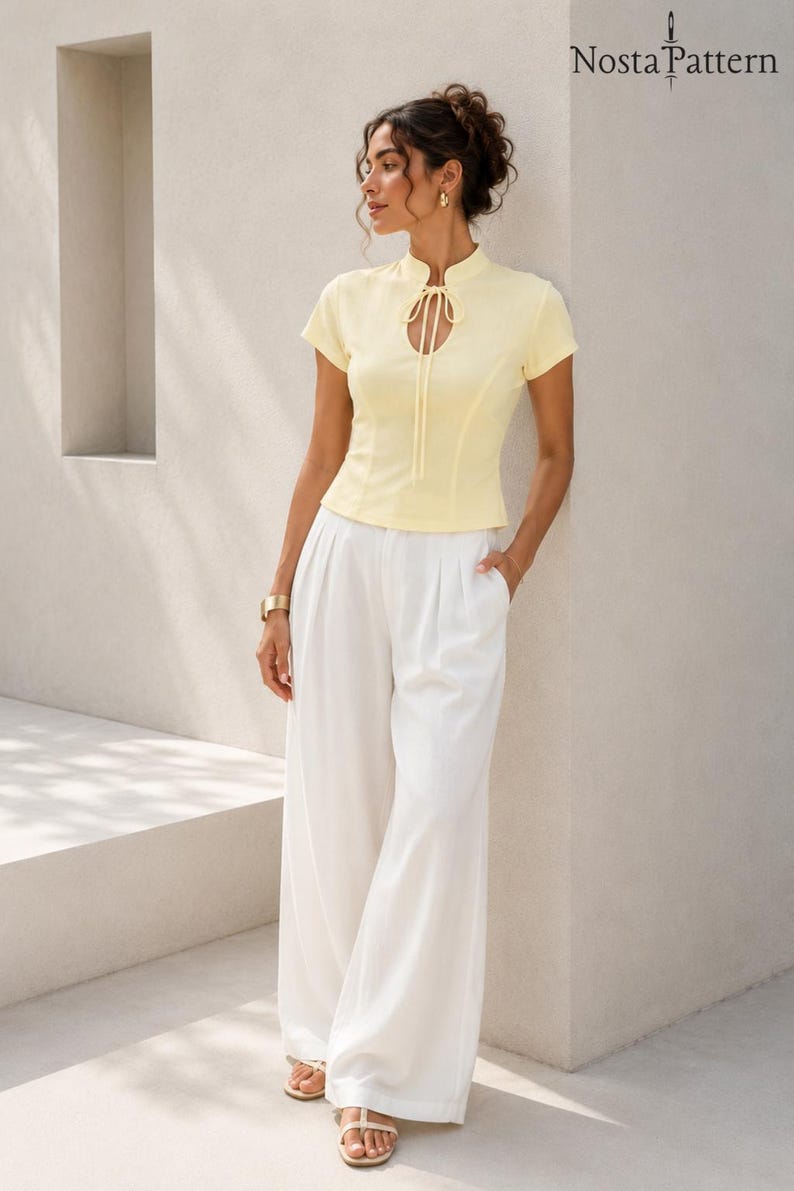 Peut inclure: Un haut jaune p&acirc;le &agrave; manches courtes avec un col officier, une encolure en trou de serrure avec un lien &agrave; nouer, et un pantalon blanc &agrave; jambes larges. Le haut est ajust&eacute; avec des coutures verticales et le pantalon a une taille pliss&eacute;e.