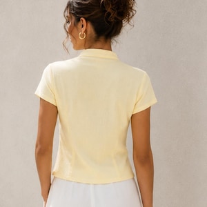 Peut inclure: Une chemise &agrave; col et manches courtes de couleur jaune p&acirc;le, vue de dos. La chemise pr&eacute;sente un col structur&eacute; et des manches courtes, port&eacute;e avec un pantalon blanc. Le texte Nosta Pattern est visible dans le coin sup&eacute;rieur droit.