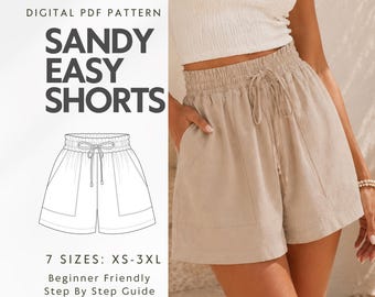 May include: A digital PDF pattern for Sandy Easy Shorts, featuring a line drawing of shorts with an elastic waistband and drawstring. The image displays beige shorts with a high-waisted elastic band, a drawstring tie, and two large front pockets.