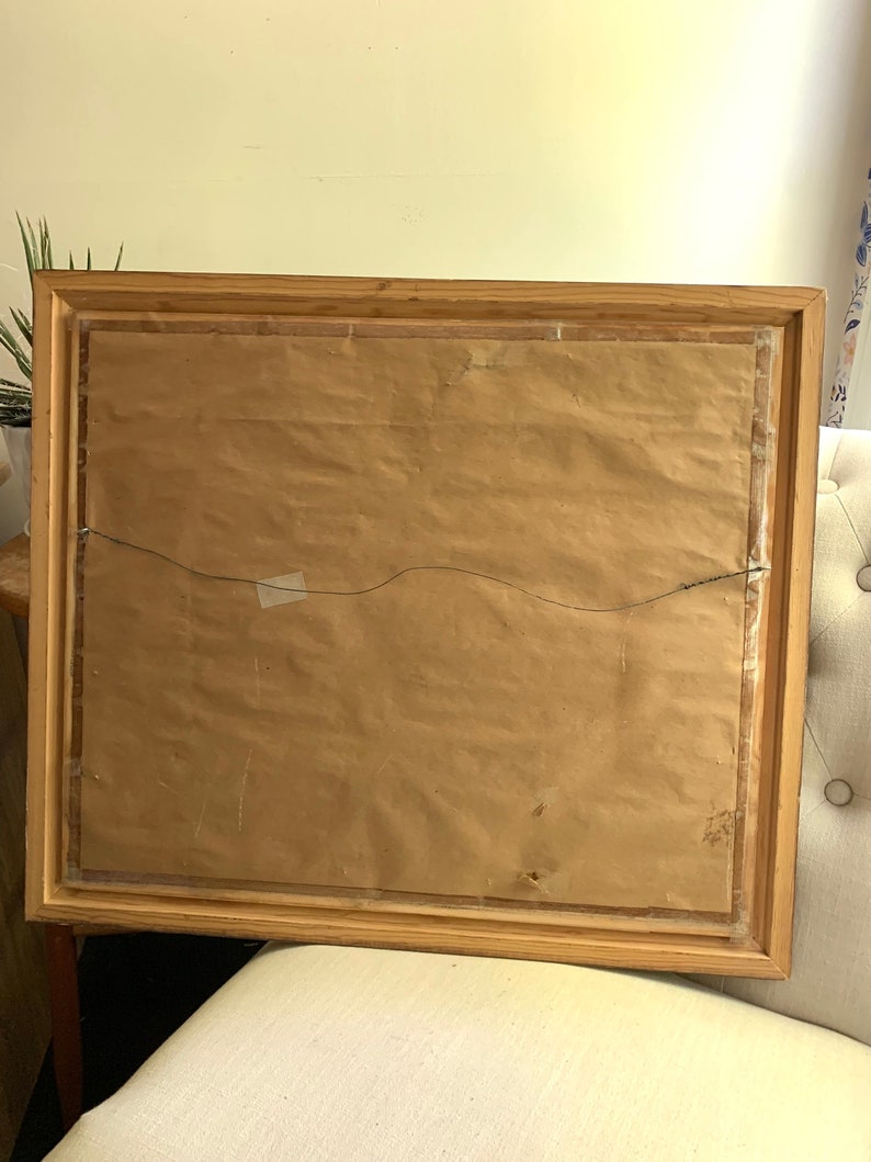 May include: A wooden picture frame with a brown paper backing and a wire hanger. The frame has a simple, rustic design.