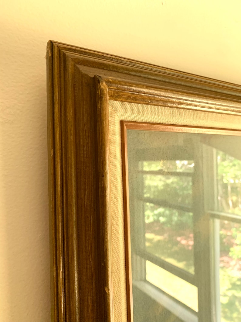 May include: A framed artwork with a brown wooden frame and a canvas backing. The artwork depicts a blurry view of a window with a green landscape outside.