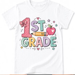 以下が含まれることがあります： 1st GRADEと書かれたカラフルなグラフィックが特徴の白い半袖Tシャツ。デザインには、リボンが付いたピンクの水玉模様の数字の1、黄色い鉛筆、ハートが描かれた赤いリンゴ、そしてパステルカラーの小さな星やハートが散りばめられています。