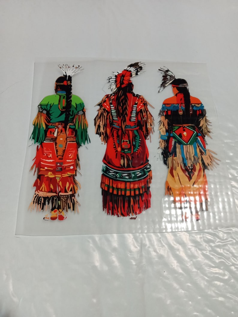 May include: Three colorful Native American figures in traditional attire. The figures are depicted from the back, showcasing detailed clothing with feathers, fringe, and intricate patterns. The color palette includes green, red, orange, and blue, creating a vibrant and cultural image.