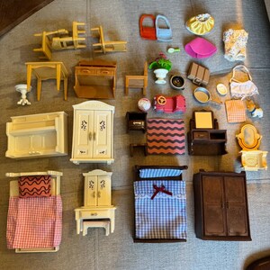 May include: A collection of miniature dollhouse furniture and accessories including beds, wardrobes, tables, chairs, a vanity, a piano, a small car, clothing items, and various household objects like a suitcase, a mirror, and a potted plant.