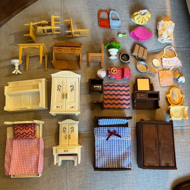 May include: A collection of miniature dollhouse furniture and accessories including beds, wardrobes, tables, chairs, a vanity, a piano, a small car, clothing items, and various household objects like a suitcase, a mirror, and a potted plant.