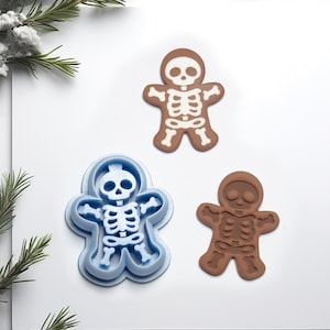 May include: Three gingerbread cookie cutters, one blue, one brown, and one white, all shaped like a skeleton gingerbread person.