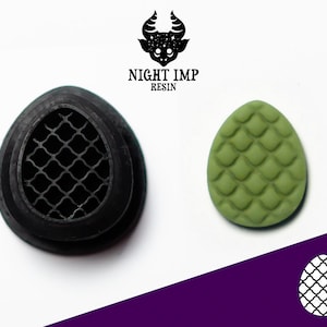 Pode incluir: Um molde de silicone preto com um padrão de grade e uma fundição de resina verde com um design de escamas de dragão. O molde e a fundição têm a forma de um ovo. O texto "NIGHT IMP RESIN" é visível acima do molde e da fundição.