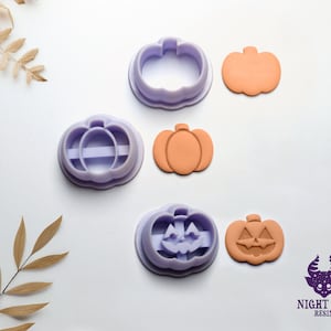 May include: Three purple plastic pumpkin cookie cutters and three orange pumpkin shapes. The pumpkin shapes have a carved face on one side and a plain pumpkin shape on the other side.