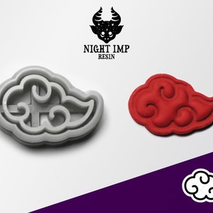 May include: A gray plastic cookie cutter shaped like a stylized cloud with a red clay impression of the same cloud design. The text "NIGHT IMP RESIN" is visible above the cookie cutter.