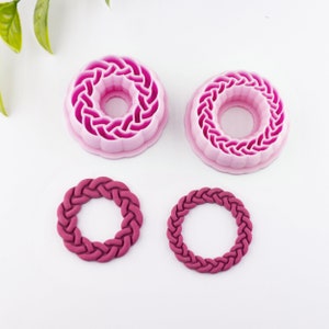 Könnte beinhalten: Zwei rosa Plastik-Kuchenformen mit geflochtenem Design und zwei kleinere rosa geflochtene Fondantformen.