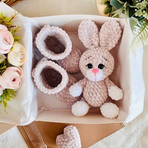 Zestaw prezentowy dla dziecka. Buciki, mały króliczek i serce w białym świątecznym opakowaniu. Produkt amigurumi wykonany z hipoalergicznej pluszowej włóczki.