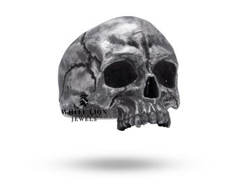 May include: A silver skull ring with a detailed design. The ring is made by White Lion Jewels.