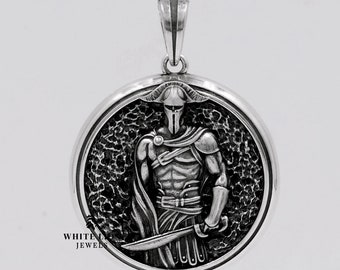 May include: Silver pendant featuring a detailed depiction of a warrior in a helmet and armor, holding a sword. The pendant is round and has a textured background.