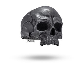 May include: A silver skull ring with detailed features. The ring is made by White Lion Jewels.