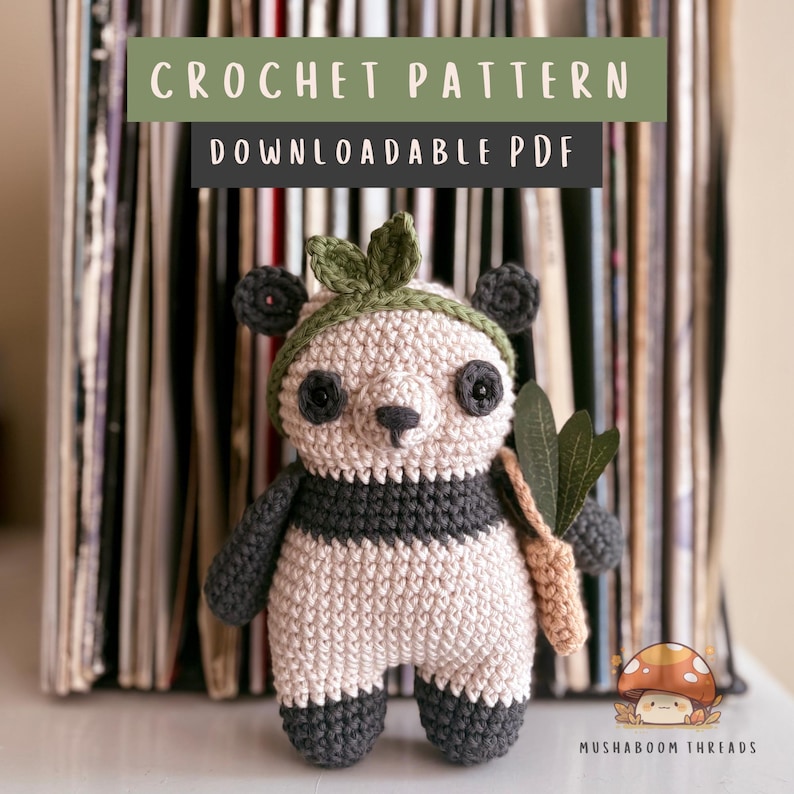 Puede incluir: Un oso panda tejido a ganchillo con una diadema de hojas verdes y una zanahoria beige. El panda es negro, blanco y gris. La imagen incluye el texto "CROCHET PATTERN DOWNLOADABLE PDF" en la parte superior y el texto "MUSHABOOM THREADS" en la parte inferior.