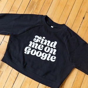 May include: Black cropped sweatshirt with white text that reads "Find me on Google" in a retro font.