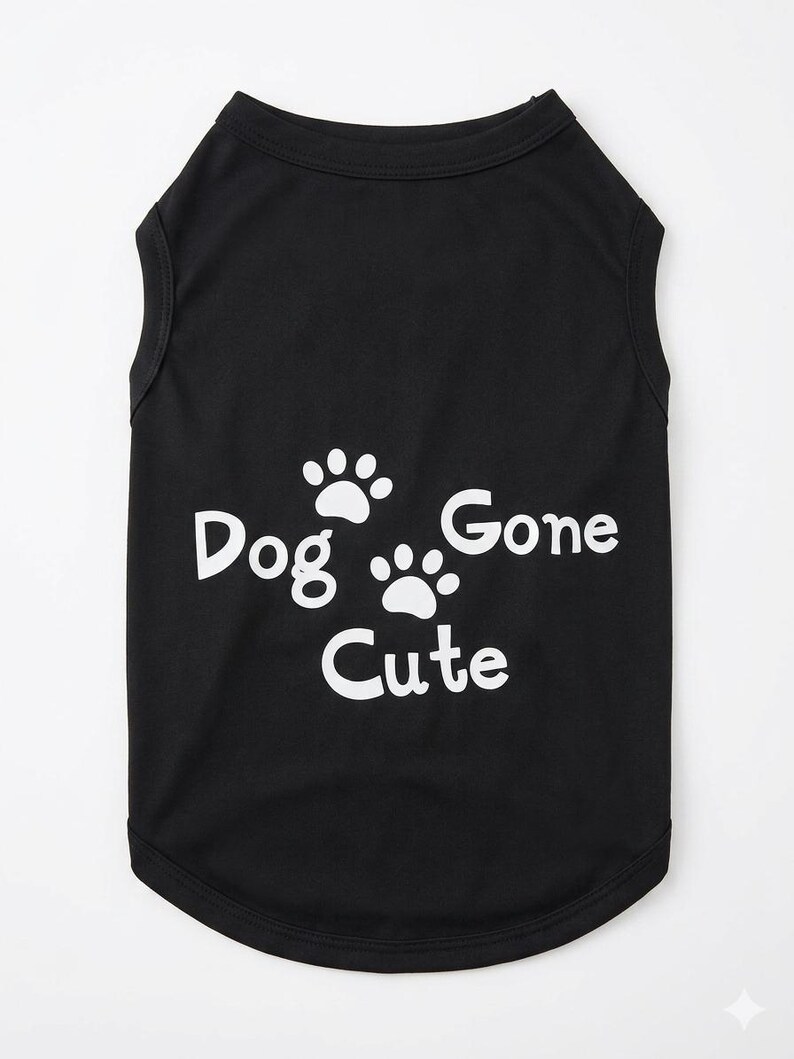 Op de afbeelding: Zwart hondenhemd met witte tekst en pootafdrukken. De tekst luidt "Dog Gone Cute". De mouwloze top is gemaakt van een zacht materiaal en heeft een afgeronde zoom.
