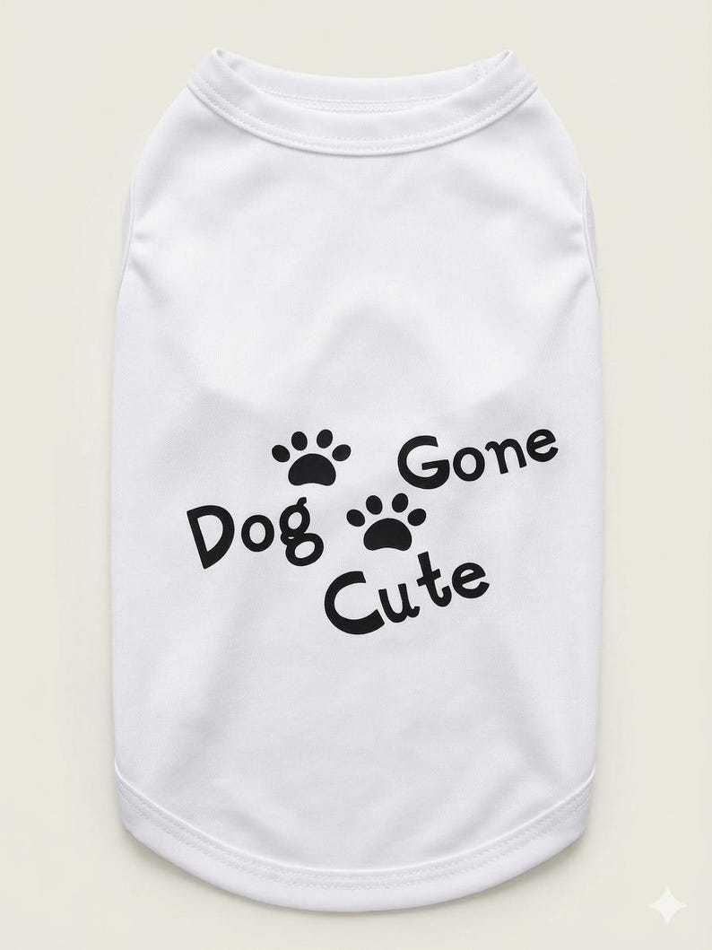 Op de afbeelding: Witte honden-T-shirt met zwarte tekst en pootafdrukken. De tekst luidt "Dog Gone Cute". Het shirt is mouwloos, waarschijnlijk voor een kleine hond of puppy.