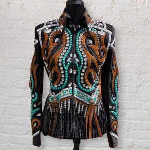 Könnte beinhalten: Eine schwarze Showjacke mit einem braunen, türkisfarbenen und silbernen Perlenmuster. Die Jacke hat einen Reißverschluss und lange Ärmel.