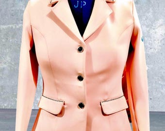 May include: A peach-colored riding jacket with black buttons and a black trim around the pockets. The jacket has the number "10" and the letters "JP" on the collar.