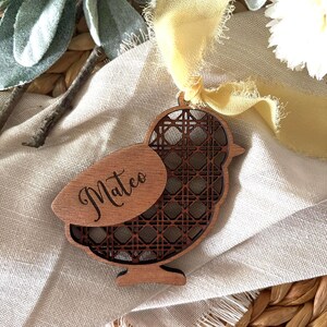 May include: A wooden bird ornament with a geometric pattern and the name "Mateo" engraved on it. The ornament is hanging from a yellow ribbon.