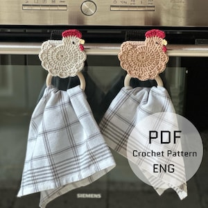 Puede incluir: Dos colgadores de toallas de cocina de pollo de ganchillo con aros de madera y toallas a cuadros grises colgadas de un horno. Los pollos son beige y blancos con crestas rojas y picos amarillos. Las toallas tienen un patrón de cuadros grises y blancos.