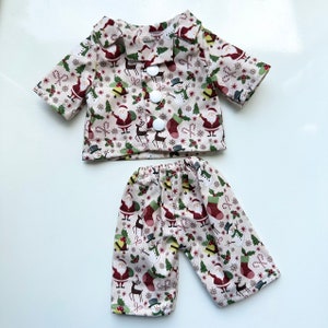 Puede incluir: Un conjunto de pijama de color crema con un estampado navide&ntilde;o que incluye Pap&aacute; Noel, renos, mu&ntilde;ecos de nieve y bastones de caramelo. El conjunto incluye una camisa de manga corta con cuello abotonado y pantalones a juego.