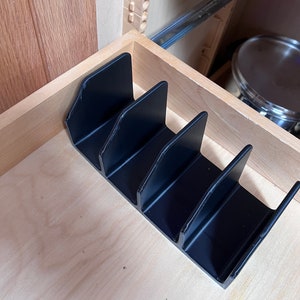 Könnte beinhalten: Schwarzer Plastik-Schubladenorganizer mit fünf Fächern. Der Organizer ist so konzipiert, dass Gegenstände aufrecht stehen.