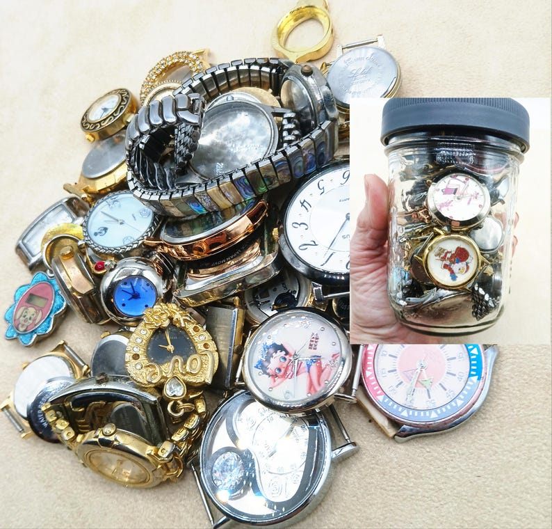 K&ouml;nnte beinhalten: Eine Sammlung verschiedener Vintage-Armbanduhren und Uhrenteile, darunter gold- und silberfarbene Modelle sowie dekorative Zifferbl&auml;tter mit Charakterillustrationen, erg&auml;nzt durch ein Glasgef&auml;&szlig; voller weiterer Uhrenkomponenten.