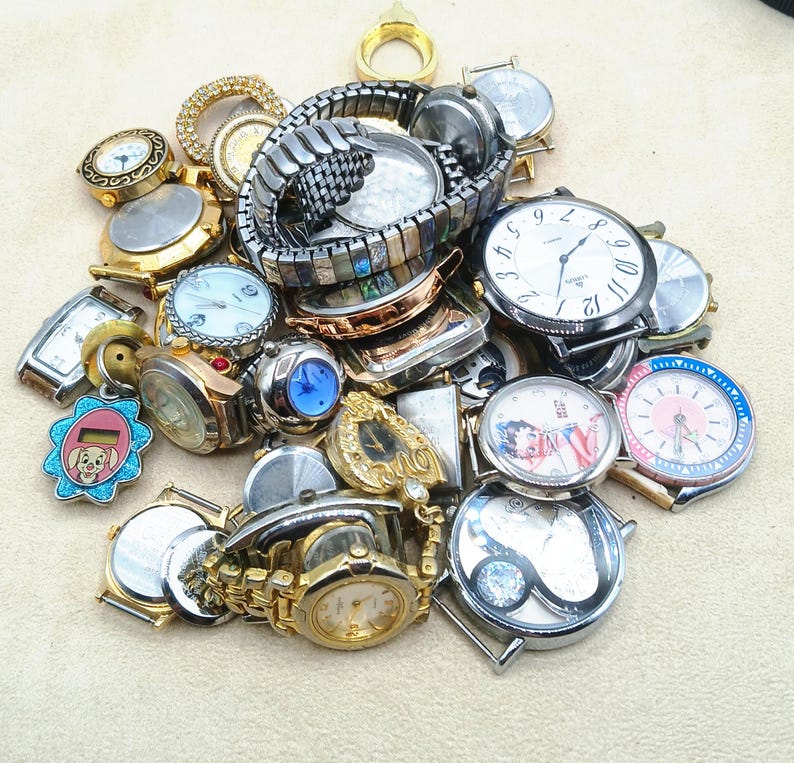 K&ouml;nnte beinhalten: Eine Sammlung verschiedener Armbanduhren und Uhrenteile in diversen Ausf&uuml;hrungen, darunter gold- und silberfarbene Modelle sowie Metallgliederarmb&auml;nder. Der Haufen enth&auml;lt runde und rechteckige Zifferbl&auml;tter, teils mit verzierten L&uuml;netten.