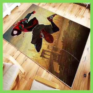 May include: A colorful rug featuring a cartoon superhero in a red and black suit, swinging from a web line over a cityscape with a bridge in the background.