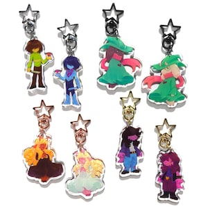 Op de afbeelding: Collectie acryl sleutelhangers met verschillende personages. Elke sleutelhanger heeft een ster-vormige sluiting. De personages zijn afgebeeld in levendige kleuren, met details zoals kleding en accessoires.