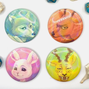 Puede incluir: Cuatro botones redondos con acabados holográficos iridiscentes. Cada botón presenta un animal diferente con un halo: un lobo, un ciervo, un conejo y un guepardo.